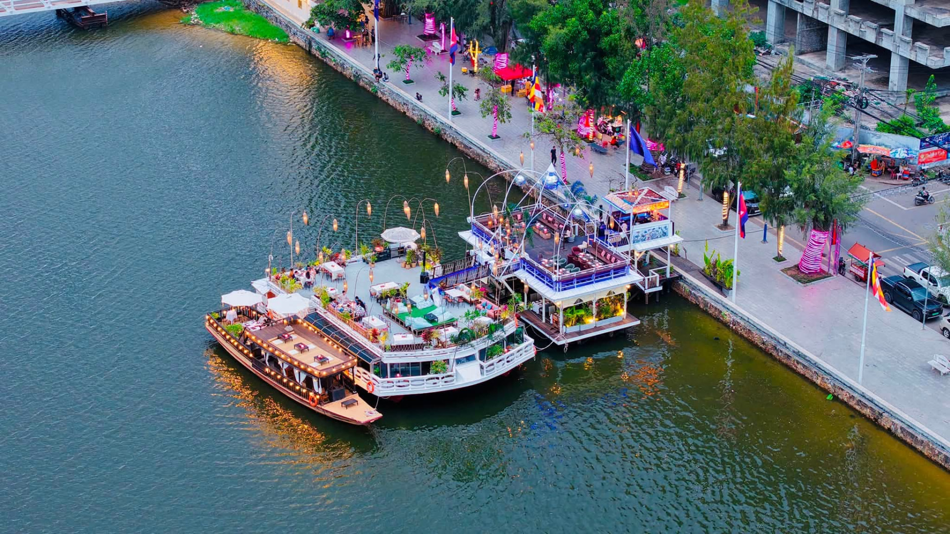 Aerial view of the Kdam Kampot floating restaurant and boats moored along the Kampot riverside
