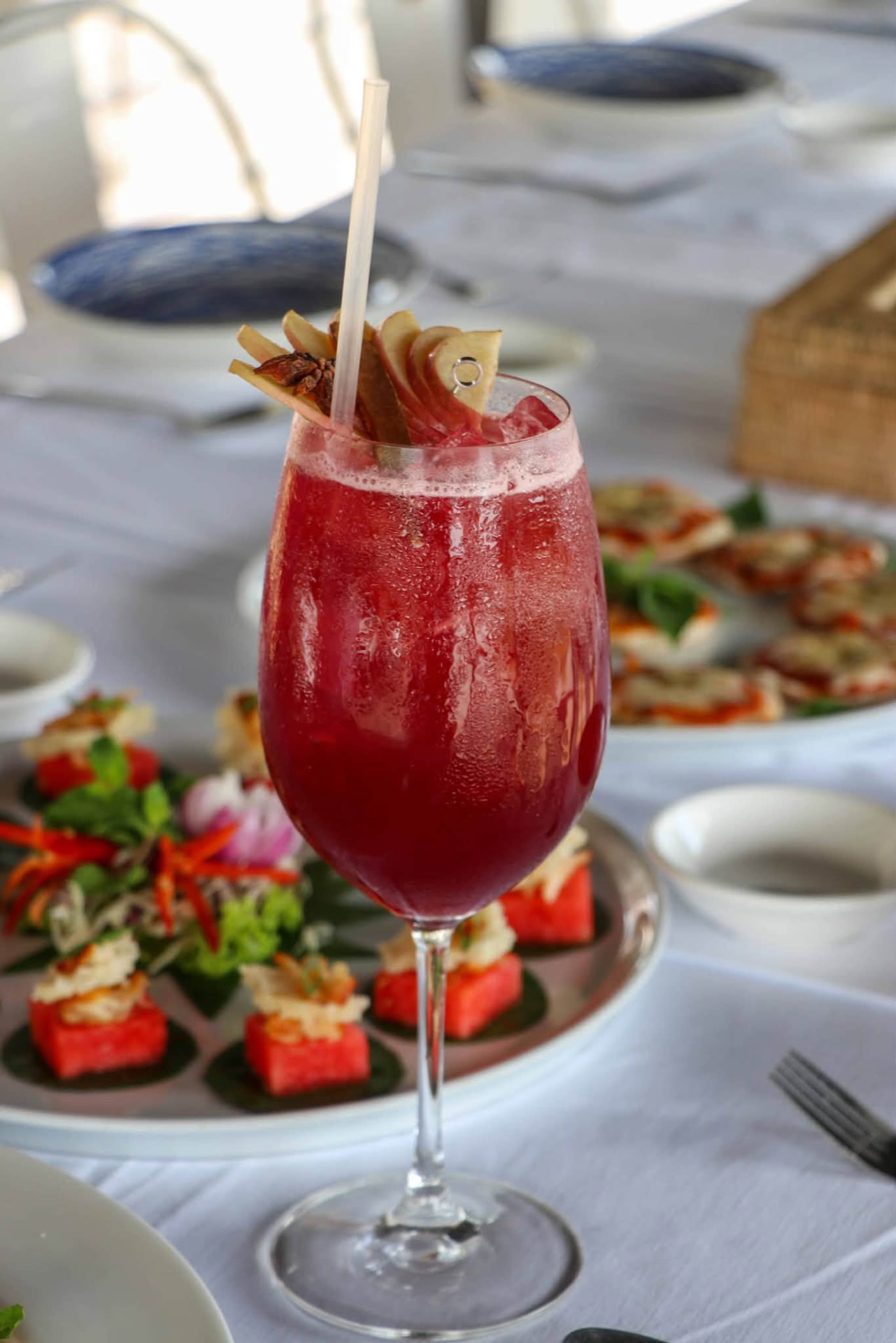 Ruby signature drink beside watermelon canapes and flatbreads on a white banquet table
